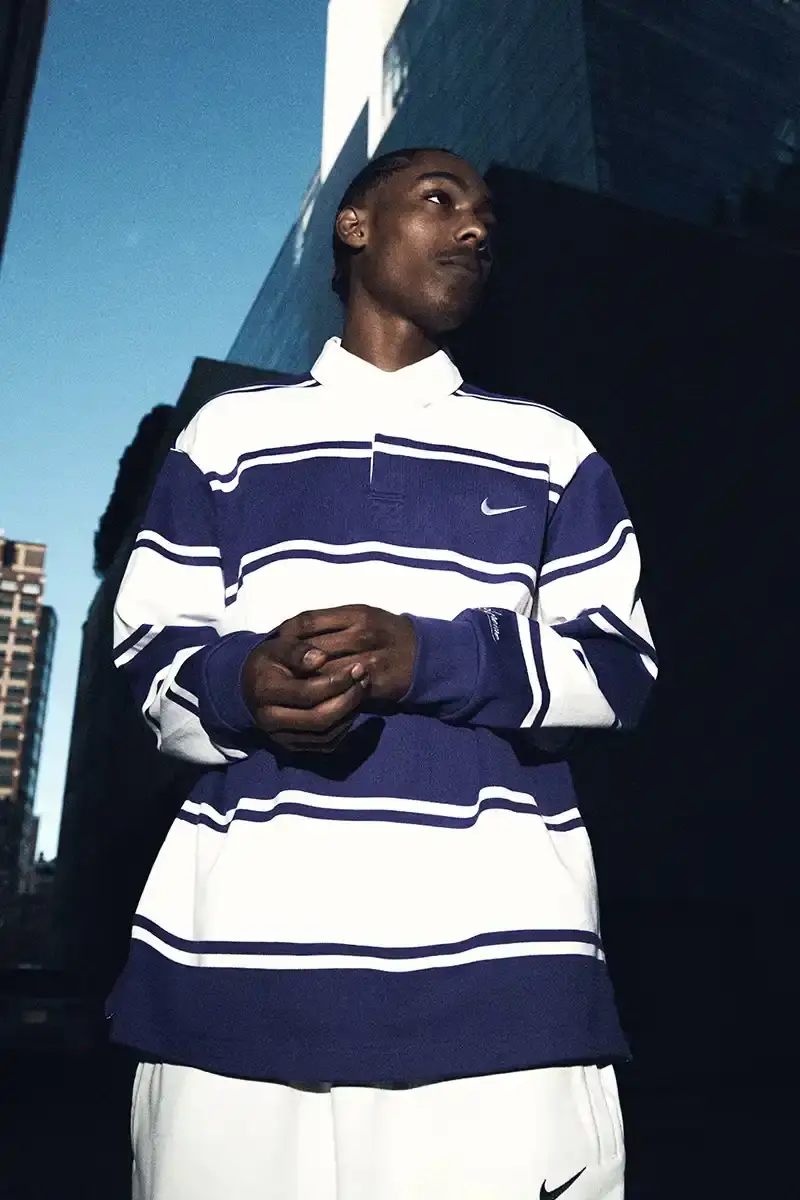 Supreme/Nike Supreme x Nike Spring 2025 Collection featuring black and white Leather Varsity Jackets, purple, yellow and black Track Suits, striped Rugby shirts, Sweater Vests, Hooded Sweatshirts, and accessories including Running Hats and Leather Shoulder Bags. (image 13 of 22)