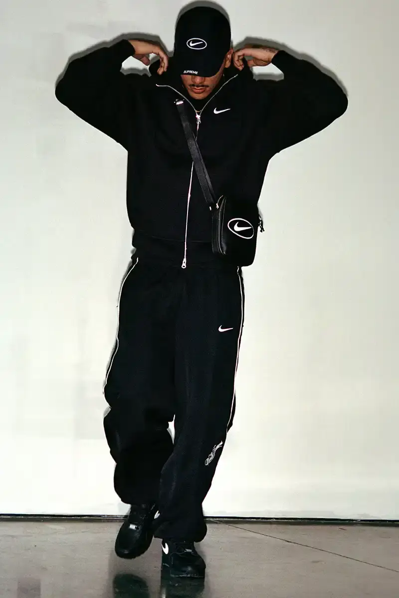 Supreme/Nike Supreme x Nike Spring 2025 Collection featuring black and white Leather Varsity Jackets, purple, yellow and black Track Suits, striped Rugby shirts, Sweater Vests, Hooded Sweatshirts, and accessories including Running Hats and Leather Shoulder Bags. (image 8 of 22)