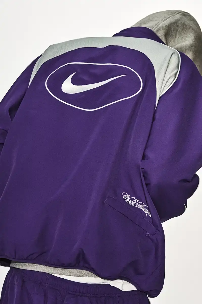 Supreme/Nike Supreme x Nike Spring 2025 Collection featuring black and white Leather Varsity Jackets, purple, yellow and black Track Suits, striped Rugby shirts, Sweater Vests, Hooded Sweatshirts, and accessories including Running Hats and Leather Shoulder Bags. (image 19 of 22)