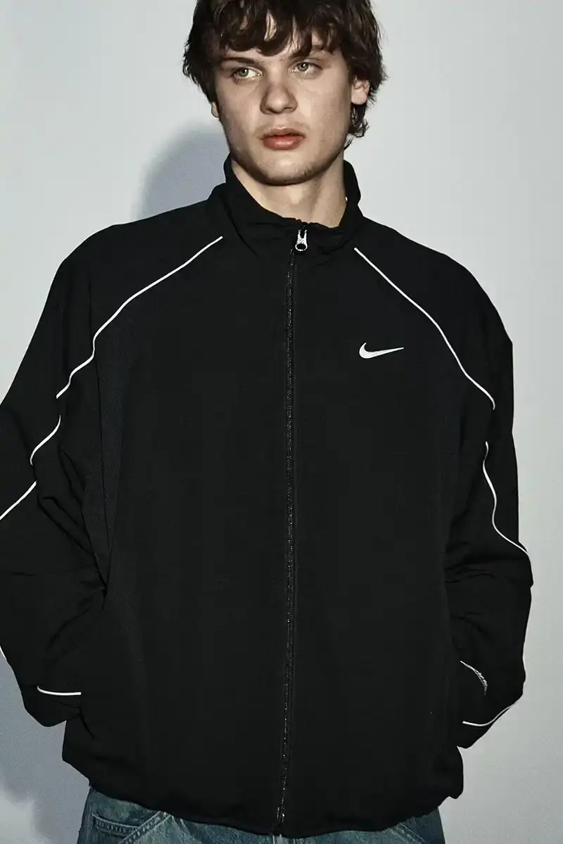Supreme/Nike Supreme x Nike Spring 2025 Collection featuring black and white Leather Varsity Jackets, purple, yellow and black Track Suits, striped Rugby shirts, Sweater Vests, Hooded Sweatshirts, and accessories including Running Hats and Leather Shoulder Bags. (image 16 of 22)