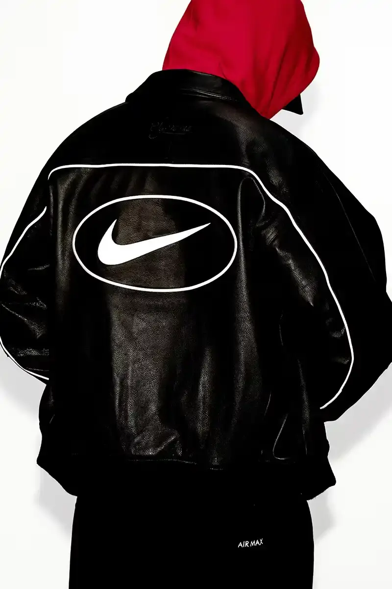 Supreme/Nike Supreme x Nike Spring 2025 Collection featuring black and white Leather Varsity Jackets, purple, yellow and black Track Suits, striped Rugby shirts, Sweater Vests, Hooded Sweatshirts, and accessories including Running Hats and Leather Shoulder Bags. (image 2 of 22)