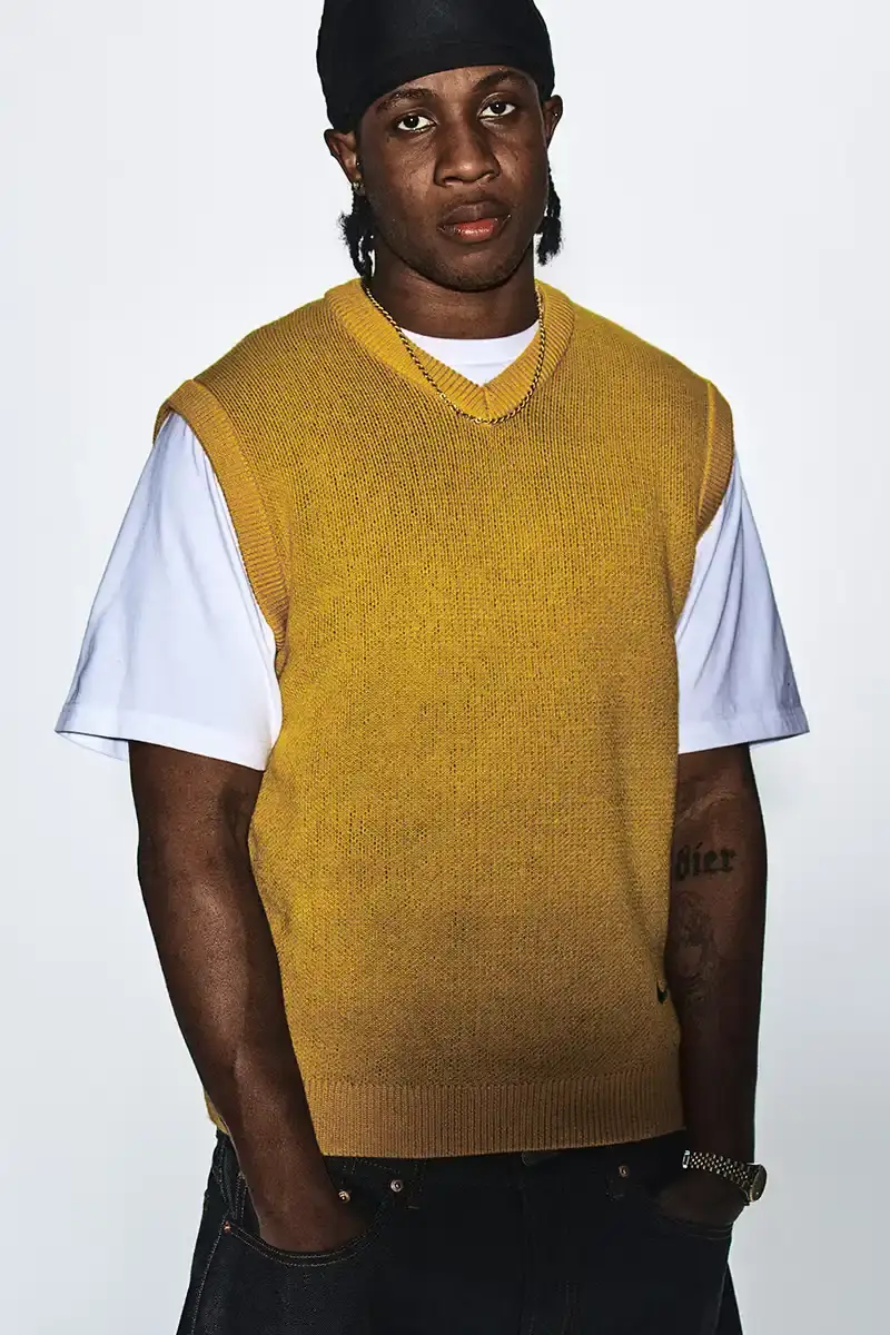 Supreme/Nike Supreme x Nike Spring 2025 Collection featuring black and white Leather Varsity Jackets, purple, yellow and black Track Suits, striped Rugby shirts, Sweater Vests, Hooded Sweatshirts, and accessories including Running Hats and Leather Shoulder Bags. (image 10 of 22)