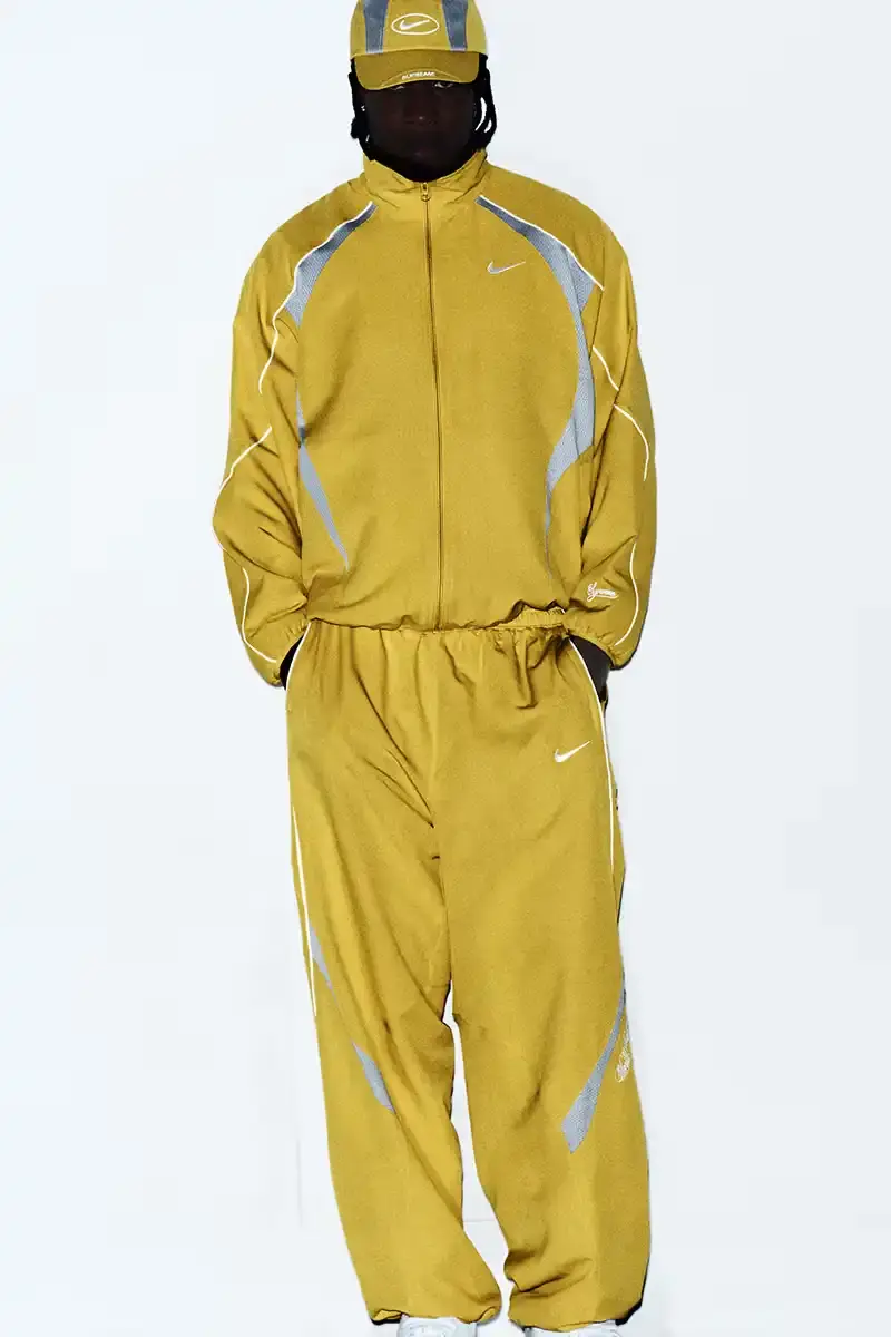 Supreme/Nike Supreme x Nike Spring 2025 Collection featuring black and white Leather Varsity Jackets, purple, yellow and black Track Suits, striped Rugby shirts, Sweater Vests, Hooded Sweatshirts, and accessories including Running Hats and Leather Shoulder Bags. (image 14 of 22)