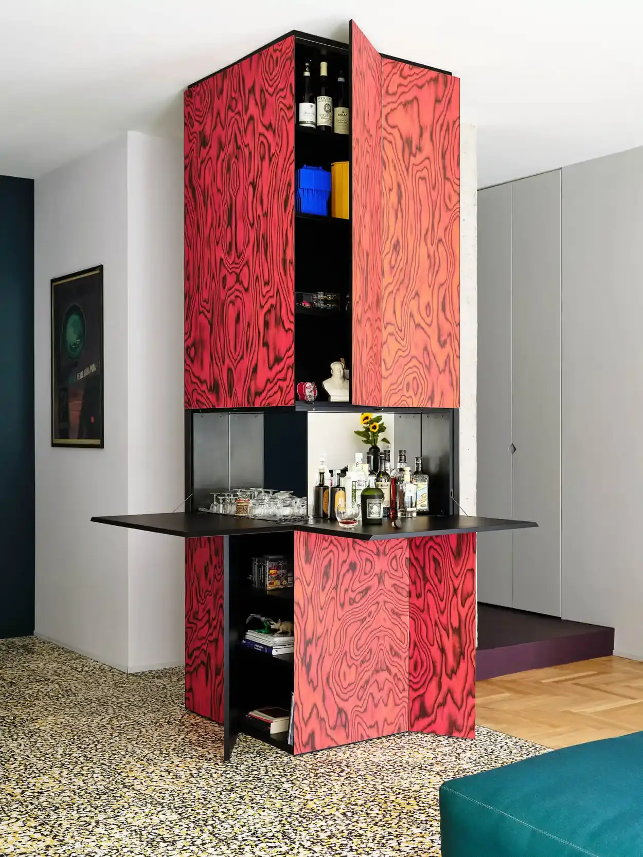Article wrote by Monica Picchi about the revival of Memphis-style decorative wood veneer, featuring colorful, psychedelic wood grain patterns pioneered by Ettore Sottsass in the 1980s and recently popularized by designers like Sabine Marcelis and Martino Gamper. The technique involves dyeing thin slices of wood to create bold, expressive patterns for furniture and interior design elements. (image 10 of 12)
