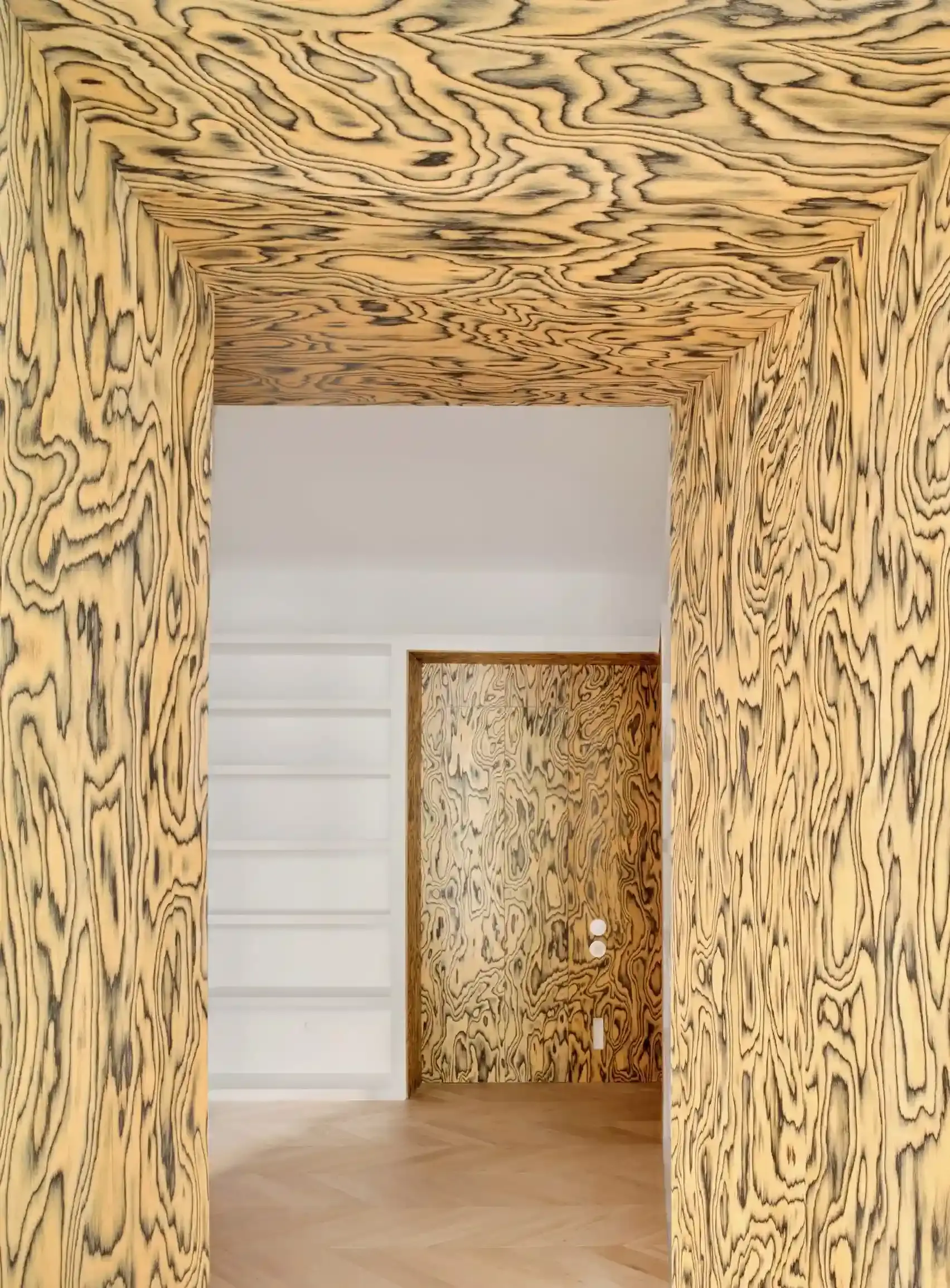 Article wrote by Monica Picchi about the revival of Memphis-style decorative wood veneer, featuring colorful, psychedelic wood grain patterns pioneered by Ettore Sottsass in the 1980s and recently popularized by designers like Sabine Marcelis and Martino Gamper. The technique involves dyeing thin slices of wood to create bold, expressive patterns for furniture and interior design elements. (image 11 of 12)