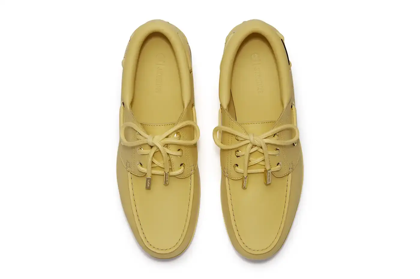 TIMBERLAND X JACQUEMUS COLLABORATION TRANSFORMS CLASSIC BOAT SHOE pictures of "La Bateau," a collaborative shoe between Timberland and Jacquemus. The design refreshes Timberland's classic 3-Eye Lug Boat Shoe with a bright yellow color and gold metal accents, including unique lace eyelets. The premium leather shoe will be available at Jacquemus stores, Timberland's Tokyo flagship, and online for £225 GBP ($250 USD). (image 3 of 5)