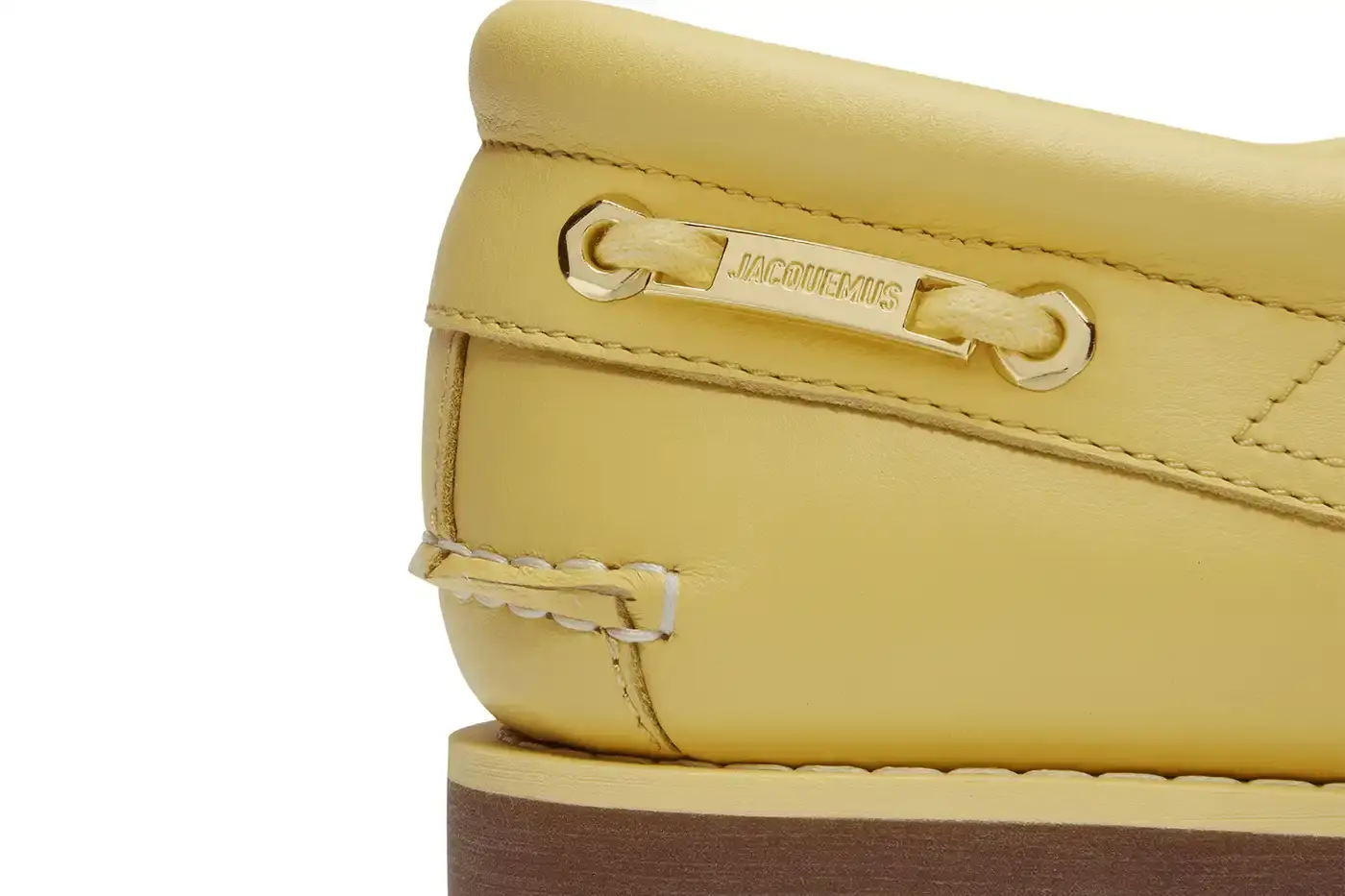 TIMBERLAND X JACQUEMUS COLLABORATION TRANSFORMS CLASSIC BOAT SHOE pictures of "La Bateau," a collaborative shoe between Timberland and Jacquemus. The design refreshes Timberland's classic 3-Eye Lug Boat Shoe with a bright yellow color and gold metal accents, including unique lace eyelets. The premium leather shoe will be available at Jacquemus stores, Timberland's Tokyo flagship, and online for £225 GBP ($250 USD). (image 5 of 5)