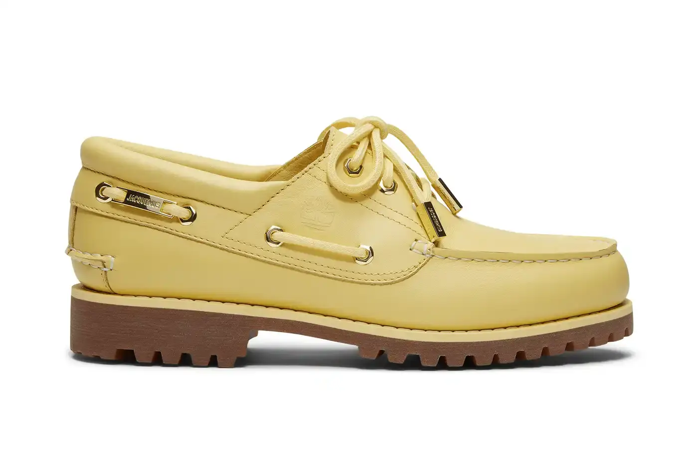 TIMBERLAND X JACQUEMUS COLLABORATION TRANSFORMS CLASSIC BOAT SHOE pictures of "La Bateau," a collaborative shoe between Timberland and Jacquemus. The design refreshes Timberland's classic 3-Eye Lug Boat Shoe with a bright yellow color and gold metal accents, including unique lace eyelets. The premium leather shoe will be available at Jacquemus stores, Timberland's Tokyo flagship, and online for £225 GBP ($250 USD). (image 2 of 5)