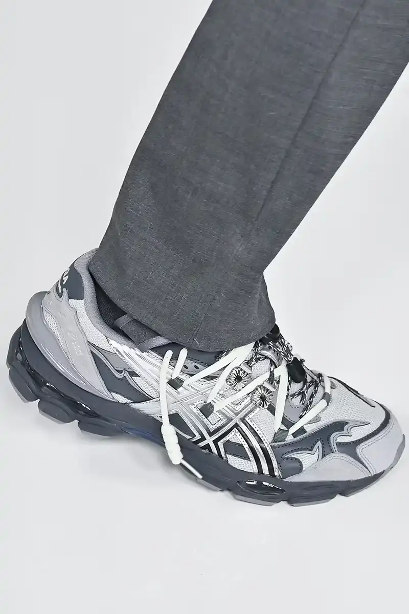 Victor Virgile/Gamma-Rapho/Getty Images TOGA x ASICS collaborative sneakers featuring decorative appliqué, dual lacing system, and ornamental hardware in gray, silver/red, and earth tone colorways.