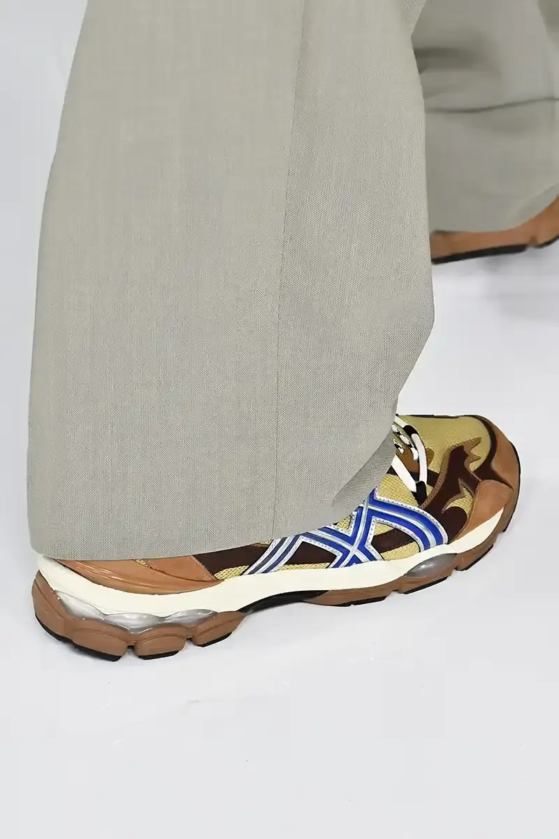 Victor Virgile/Gamma-Rapho/Getty Images TOGA x ASICS collaborative sneakers featuring decorative appliqué, dual lacing system, and ornamental hardware in gray, silver/red, and earth tone colorways. (image 3 of 5)