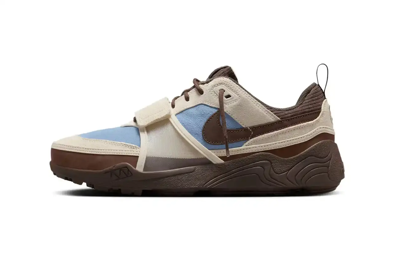 NIKE UNVEILS TRAVIS SCOTT'S ZOOM FIELD JAXX IN "LECHE BLUE" Image of the upcoming release of the Travis Scott x Nike Zoom Field Jaxx sneaker in "Leche Blue" colorway. It details the shoe's design inspiration from the Zoom Spiridon runner and Land Shark baseball cleat, describes the blue and brown color scheme, mentions the $170 price point, and notes the May 16 release date through Nike SNKRS and select retailers.