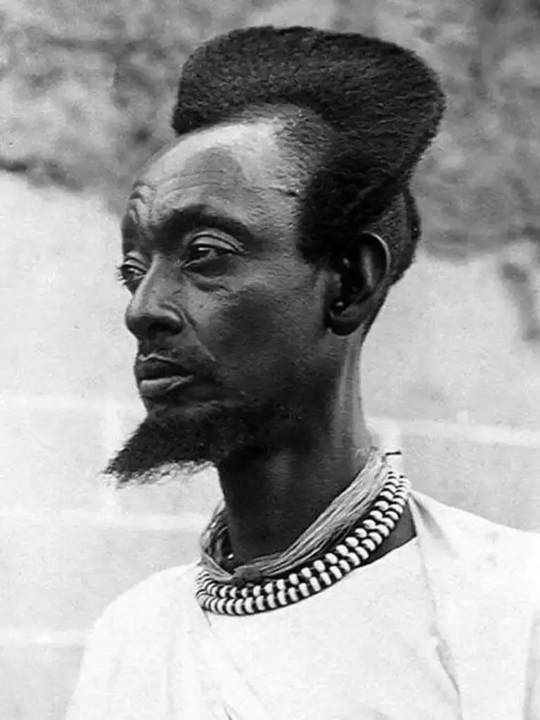Traditional Rwandan Amasunzu hairstyle showing intricate crescent-shaped patterns and precise geometric shaving. (image 3 of 6)