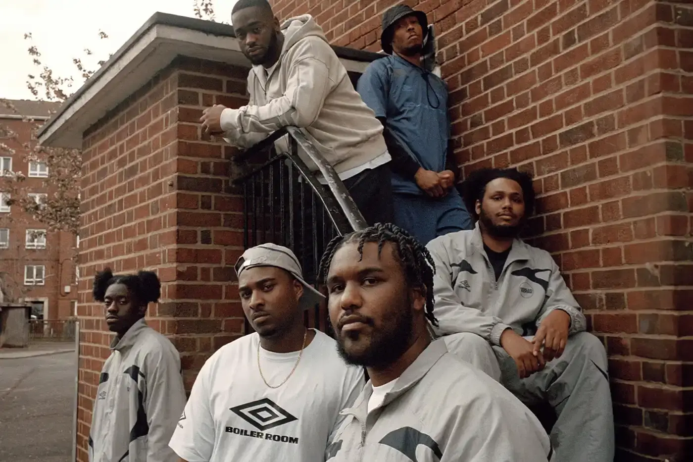 SOUTH LONDON'S FINEST: UMBRO TEAMS UP WITH BOILER ROOM AGAIN image of Umbro's third collaboration with Boiler Room, featuring a clothing collection modeled by UK artists from South London. The collection includes grey tracksuits with black accents, co-branded t-shirts, football jerseys, and hoodies. All items photographed by Simon Wheatley in Lewisham and will be available from both brands on May 15.
