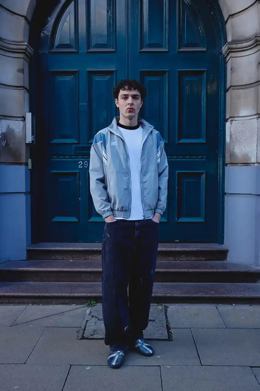 Umbro Umbro SS25 Northern Quarter collection featuring redesigned sportswear classics in white, red, black and charcoal gray, including the Zip Off Sleeve Wind Jacket and '90s-inspired Washed Drill pieces that blend Manchester heritage with contemporary design. (image 9 of 15)