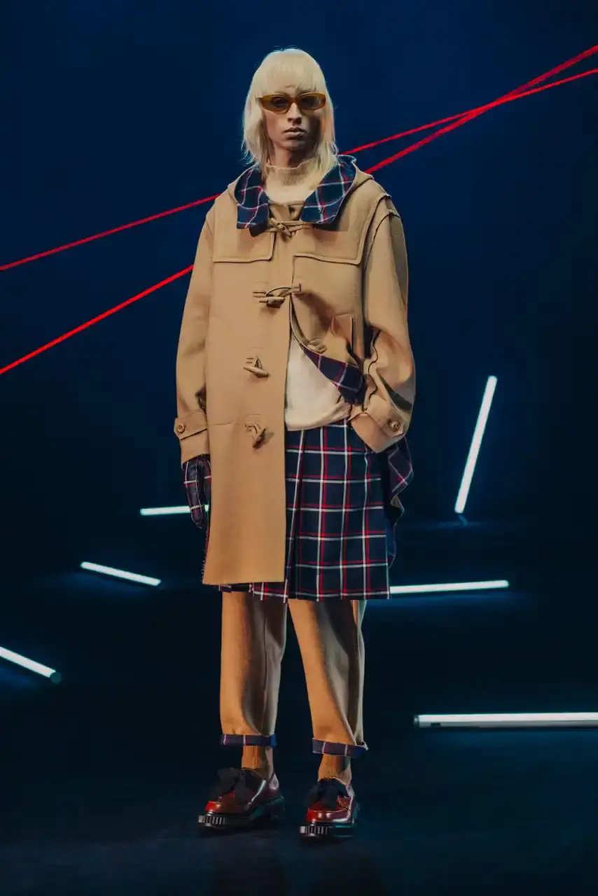 UNDERCOVER Fashion runway image featuring models wearing black tailoring and graphic prints, with neon lighting and monster illustrations by Josep Baqué, representing UNDERCOVER's FW25 collection exploring punk and musical subcultures. (image 3 of 20)