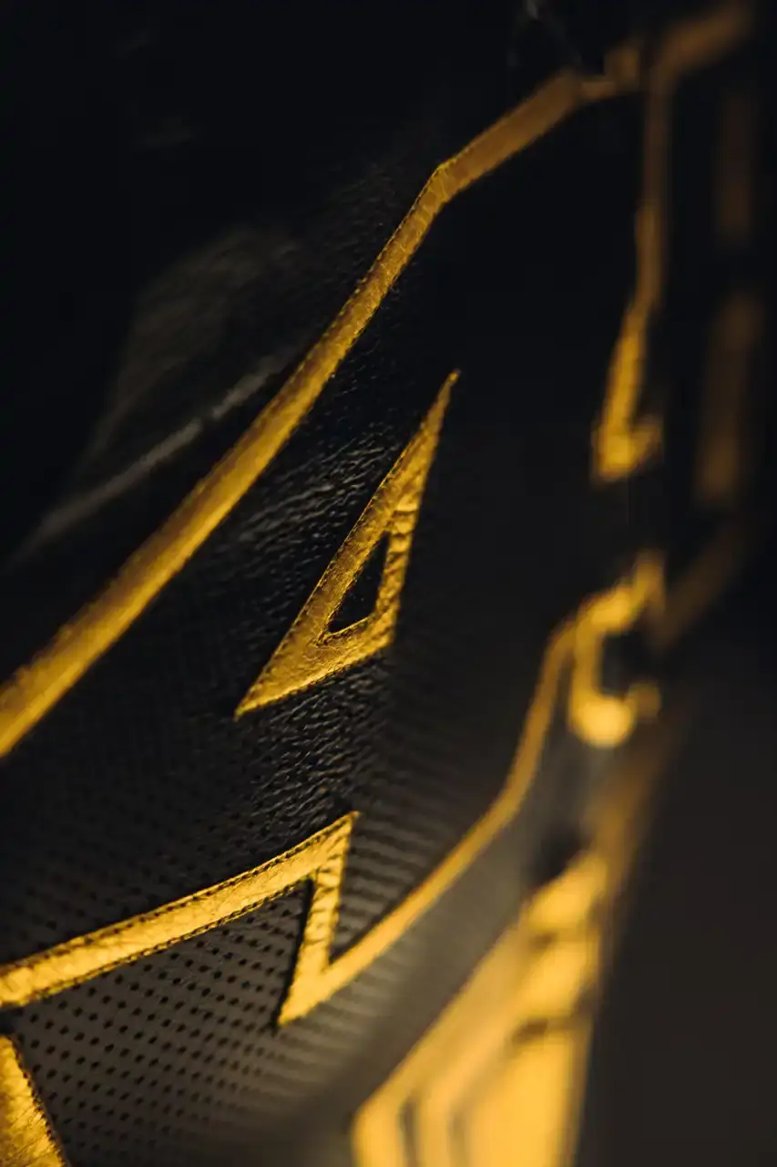 Dainese Dainese's Soleluna Vale46 Anniversary Kit displaying a black racing suit and helmet with yellow accents and gold leaf details, positioned in a glass display case. The gear features Valentino Rossi's signature number 46. (image 4 of 11)