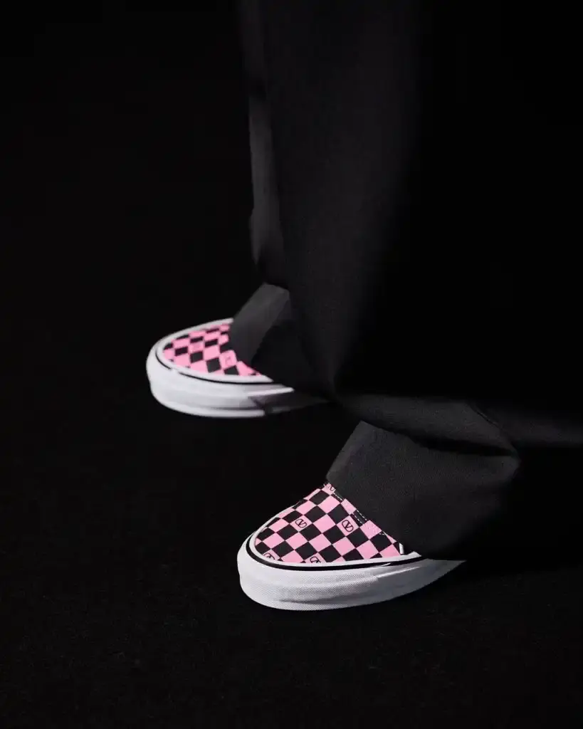 VALENTINO TEAMS UP WITH VANS IN SURPRISING COLLAB Image shows Valentino x Vans collaboration sneakers featuring checkerboard patterns with Valentino's "V" logo in white, red, pink, and black color schemes, displayed on runway models during Paris Fashion Week in a public bathroom-themed set. (image 2 of 3)