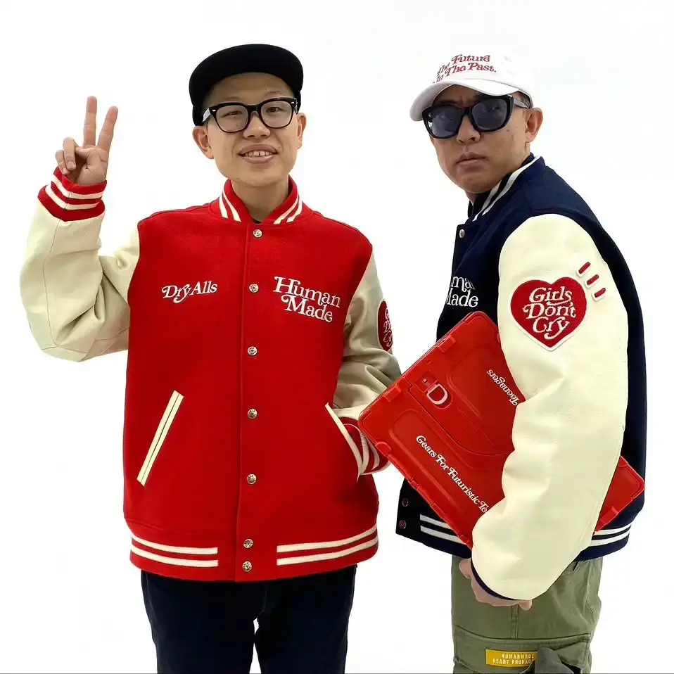Japanese streetwear designers NIGO and VERDY shake hands in a stylish studio setting, symbolizing their new partnership at HUMAN MADE.