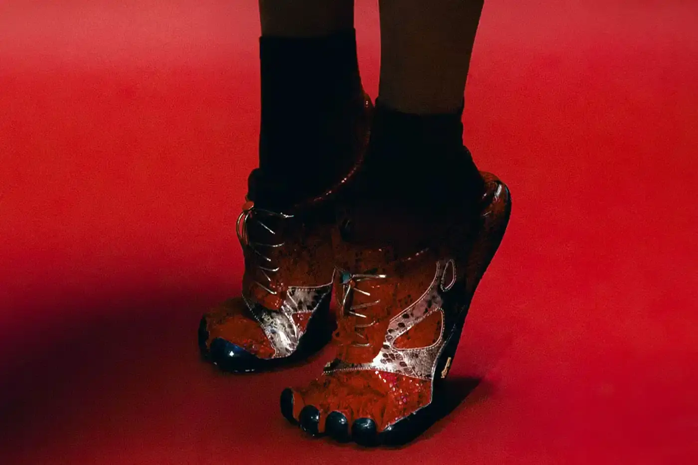 Vibram Vibram KSO Evo minimalist toe shoe in bright red with snakeskin-textured upper pattern. The shoe has individual toe pockets and a thin, flexible sole typical of FiveFingers footwear design. Viewed from a side angle showing the distinctive snake scale pattern across the mesh material. (image 2 of 10)
