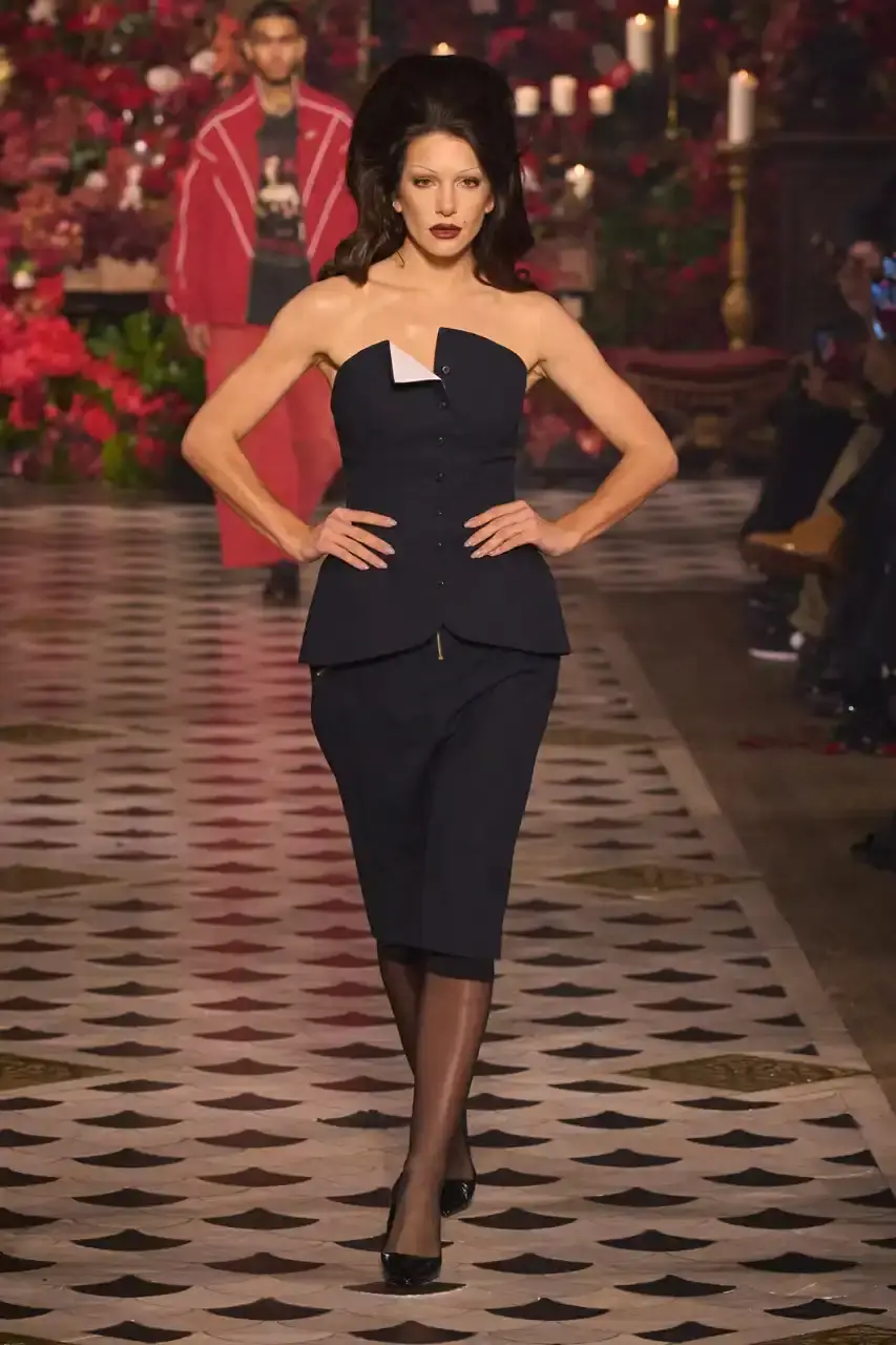 Daniele Oberrauch/Gorunway.com/Vogue Runway A diverse runway scene featuring models of various ages, body types, and backgrounds wearing Willy Chavarria's Fall 2025 "Tarantula" collection. The designs showcase rose-adorned blazers, Western-inspired hats, and a rich color palette of gold, blue, crimson, and plum against the backdrop of The American Cathedral in Paris. (image 4 of 15)