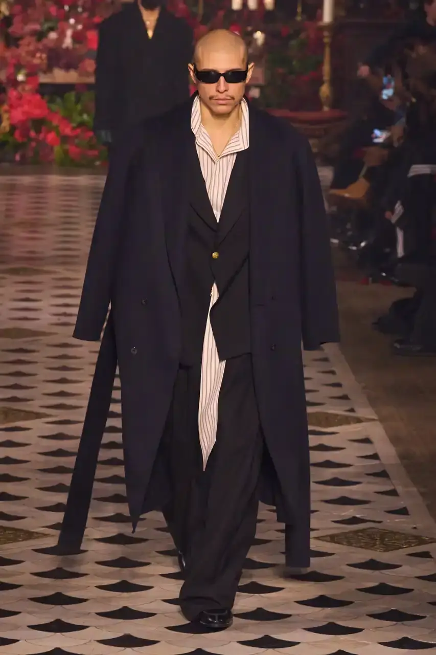 Daniele Oberrauch/Gorunway.com/Vogue Runway A diverse runway scene featuring models of various ages, body types, and backgrounds wearing Willy Chavarria's Fall 2025 "Tarantula" collection. The designs showcase rose-adorned blazers, Western-inspired hats, and a rich color palette of gold, blue, crimson, and plum against the backdrop of The American Cathedral in Paris. (image 15 of 15)