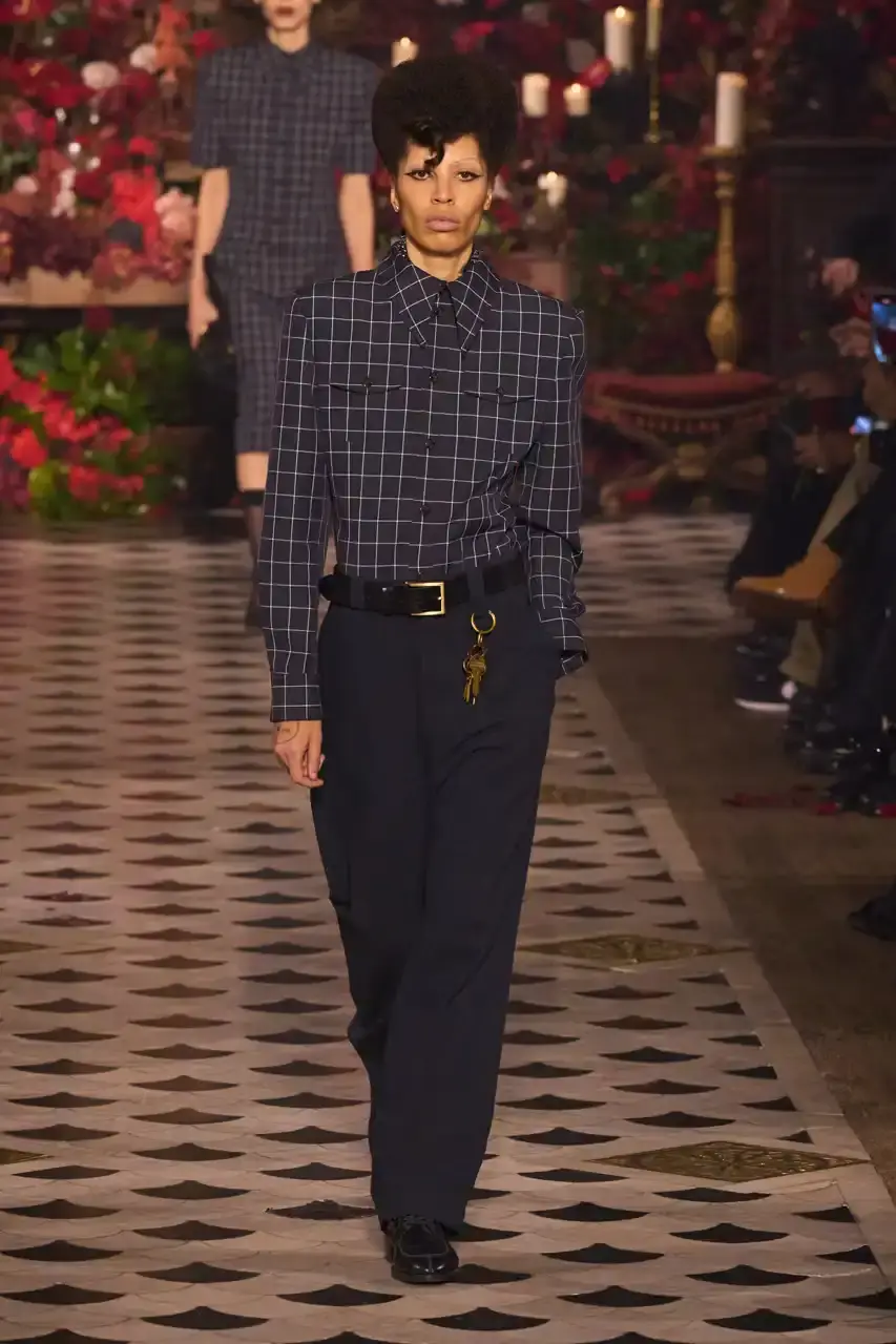 Daniele Oberrauch/Gorunway.com/Vogue Runway A diverse runway scene featuring models of various ages, body types, and backgrounds wearing Willy Chavarria's Fall 2025 "Tarantula" collection. The designs showcase rose-adorned blazers, Western-inspired hats, and a rich color palette of gold, blue, crimson, and plum against the backdrop of The American Cathedral in Paris. (image 6 of 15)