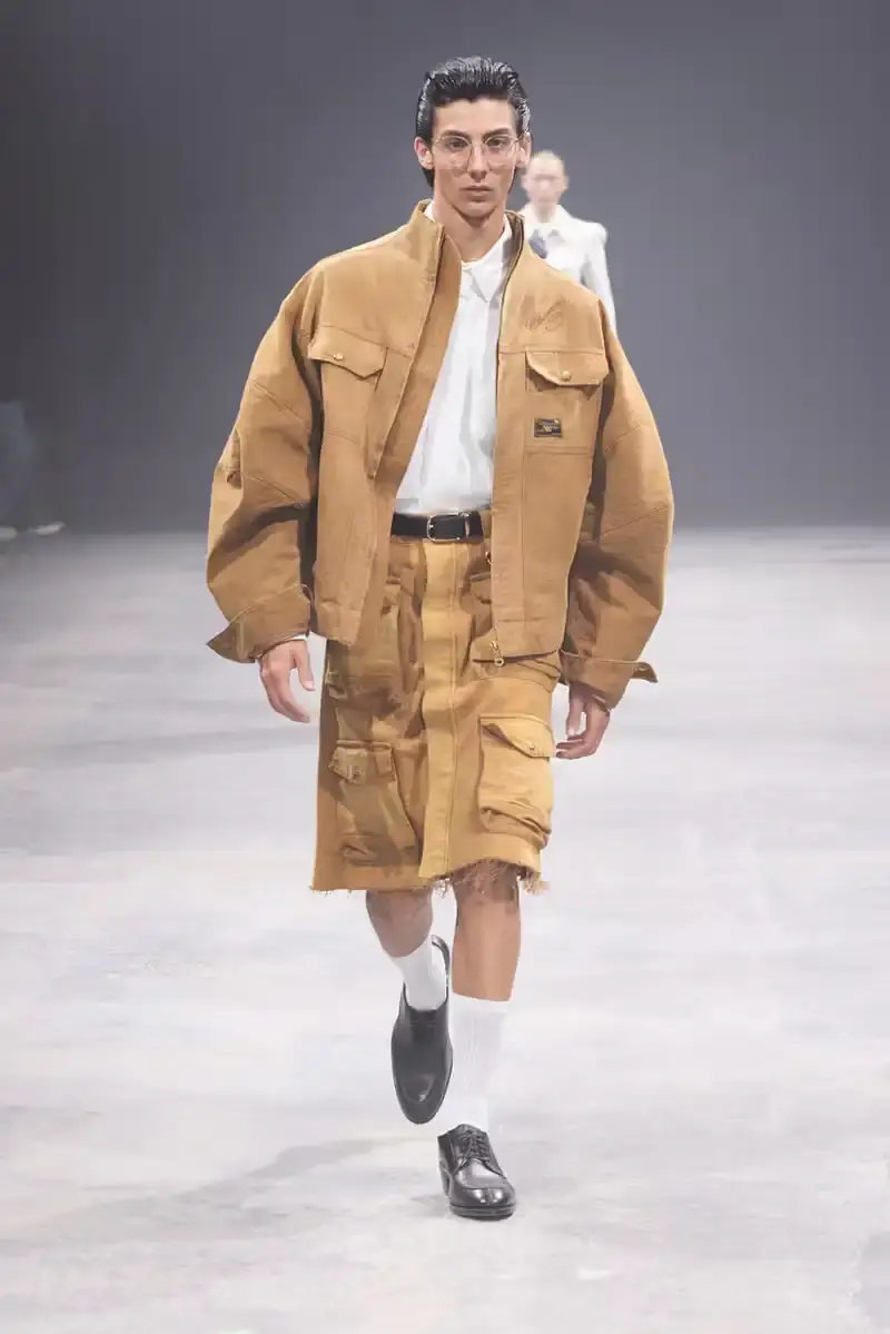WILLY CHAVARRIA SS25: A SARTORIAL ODE TO THE AMERICAN DREAM Models walk the runway at Willy Chavarria's SS25 'América' show, wearing dramatic workwear-inspired designs against an industrial backdrop (image 4 of 15)