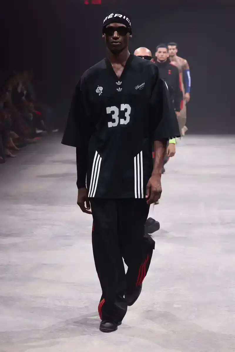 WILLY CHAVARRIA SS25: A SARTORIAL ODE TO THE AMERICAN DREAM Athletic model showcasing Willy Chavarria x adidas collaboration: avant-garde quarter-zip jacket with prominent Three Stripes logo (image 12 of 15)