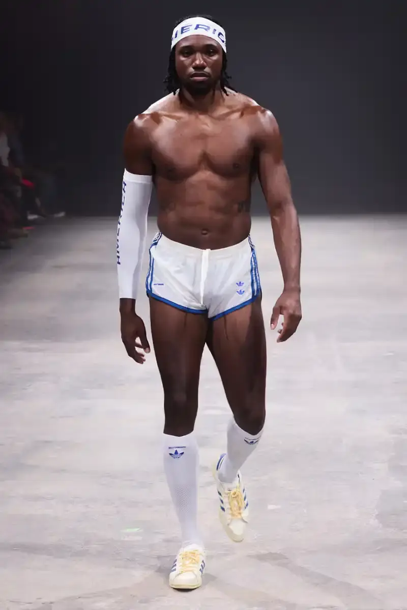 WILLY CHAVARRIA SS25: A SARTORIAL ODE TO THE AMERICAN DREAM Athletic model showcasing Willy Chavarria x adidas collaboration: avant-garde quarter-zip jacket with prominent Three Stripes logo (image 14 of 15)