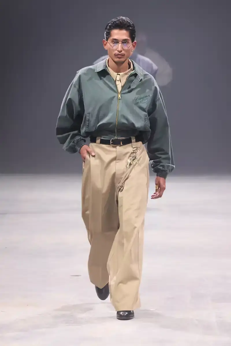 Willy Chavarria Models walk the runway at Willy Chavarria's SS25 'América' show, wearing dramatic workwear-inspired designs against an industrial backdrop