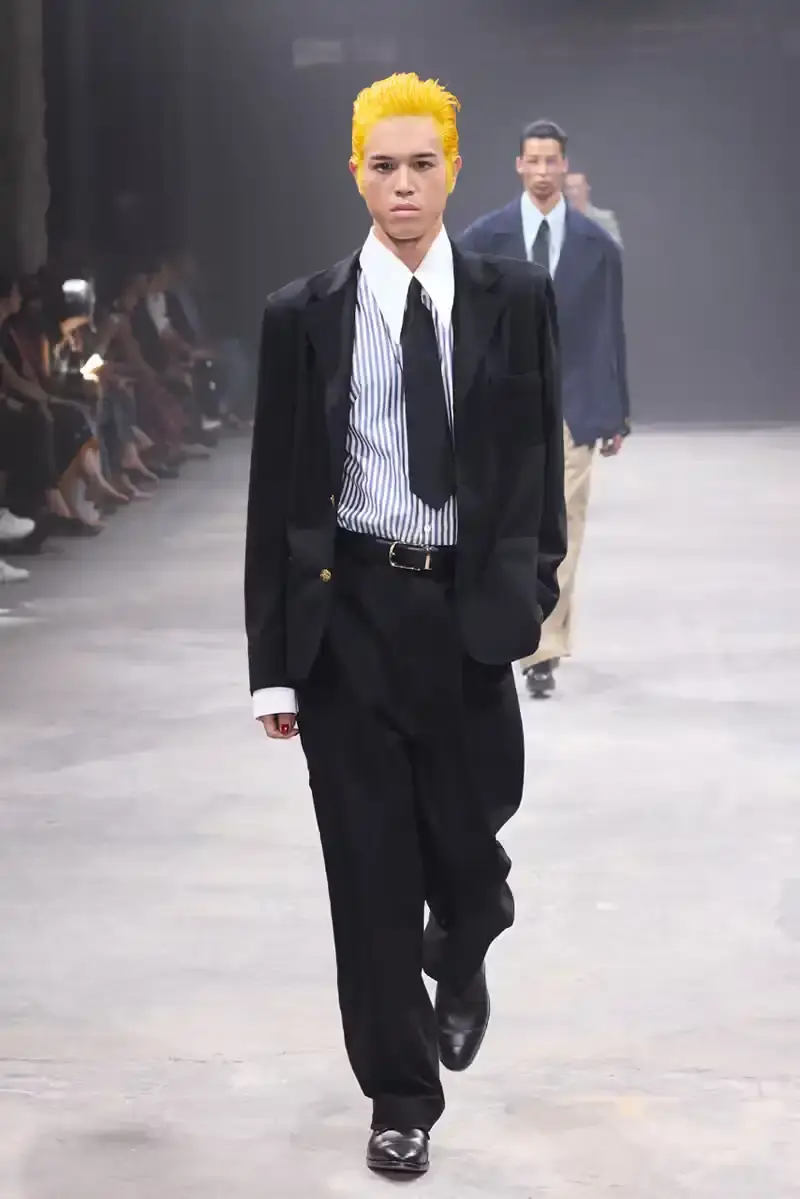 WILLY CHAVARRIA SS25: A SARTORIAL ODE TO THE AMERICAN DREAM Models walk the runway at Willy Chavarria's SS25 'América' show, wearing dramatic workwear-inspired designs against an industrial backdrop (image 6 of 15)