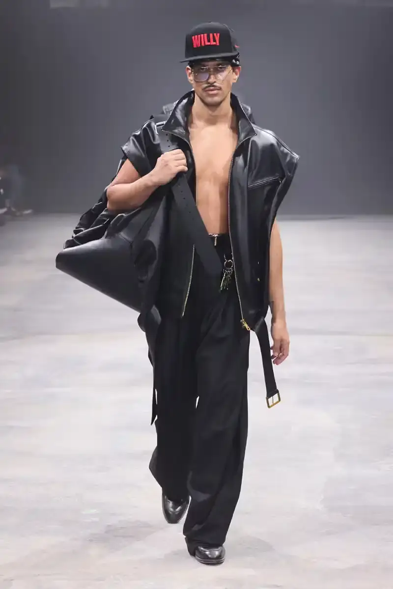 WILLY CHAVARRIA SS25: A SARTORIAL ODE TO THE AMERICAN DREAM Models walk the runway at Willy Chavarria's SS25 'América' show, wearing dramatic workwear-inspired designs against an industrial backdrop (image 5 of 15)