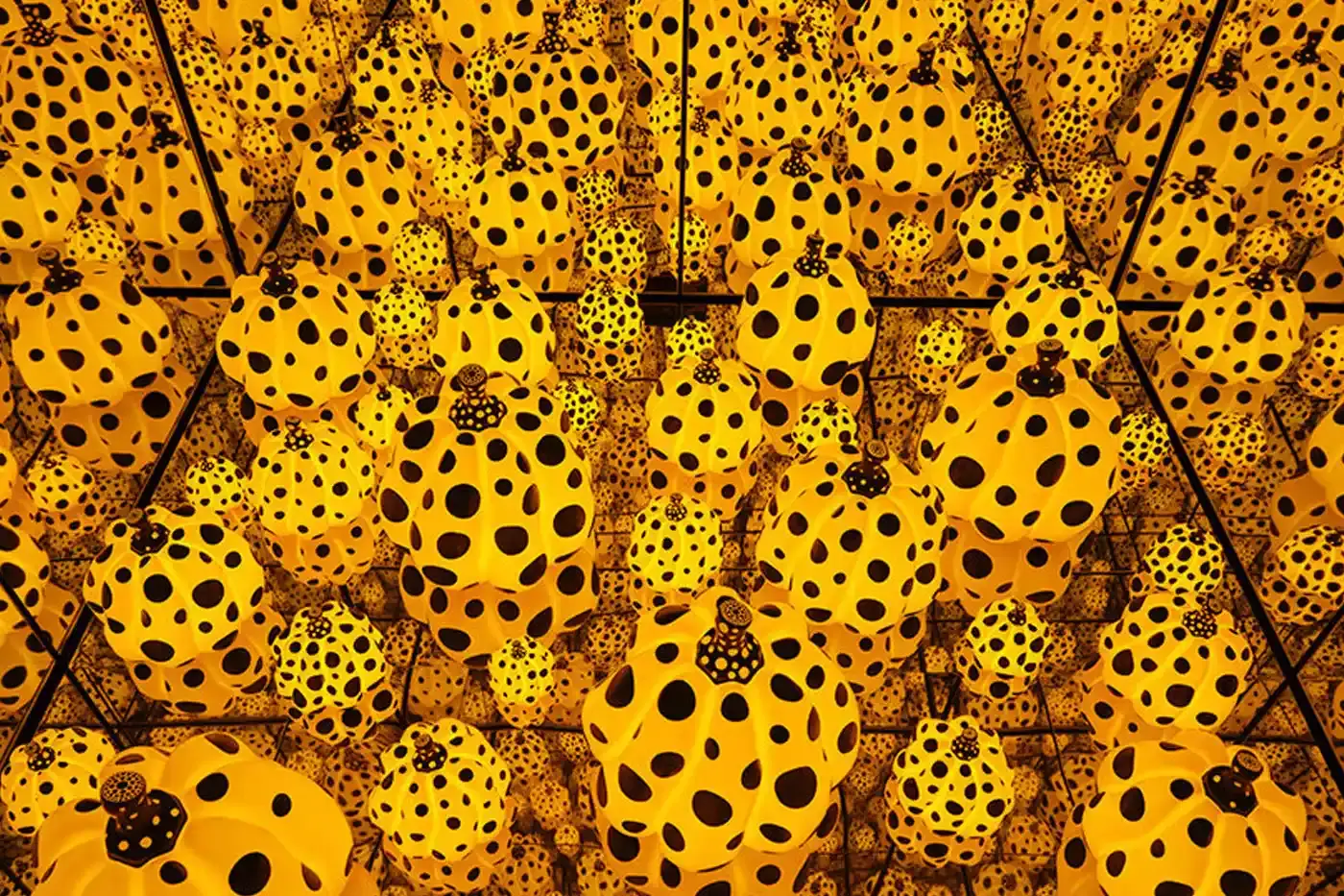 Sean Fennessy/Yayoi Kusama A photograph of Yayoi Kusama's immersive infinity mirrored room, featuring reflective surfaces creating a kaleidoscopic environment of endless light and geometric patterns. Polka-dotted sculptures and vibrant yellow and black elements are visible, representing the artist's signature visual style. (image 2 of 13)