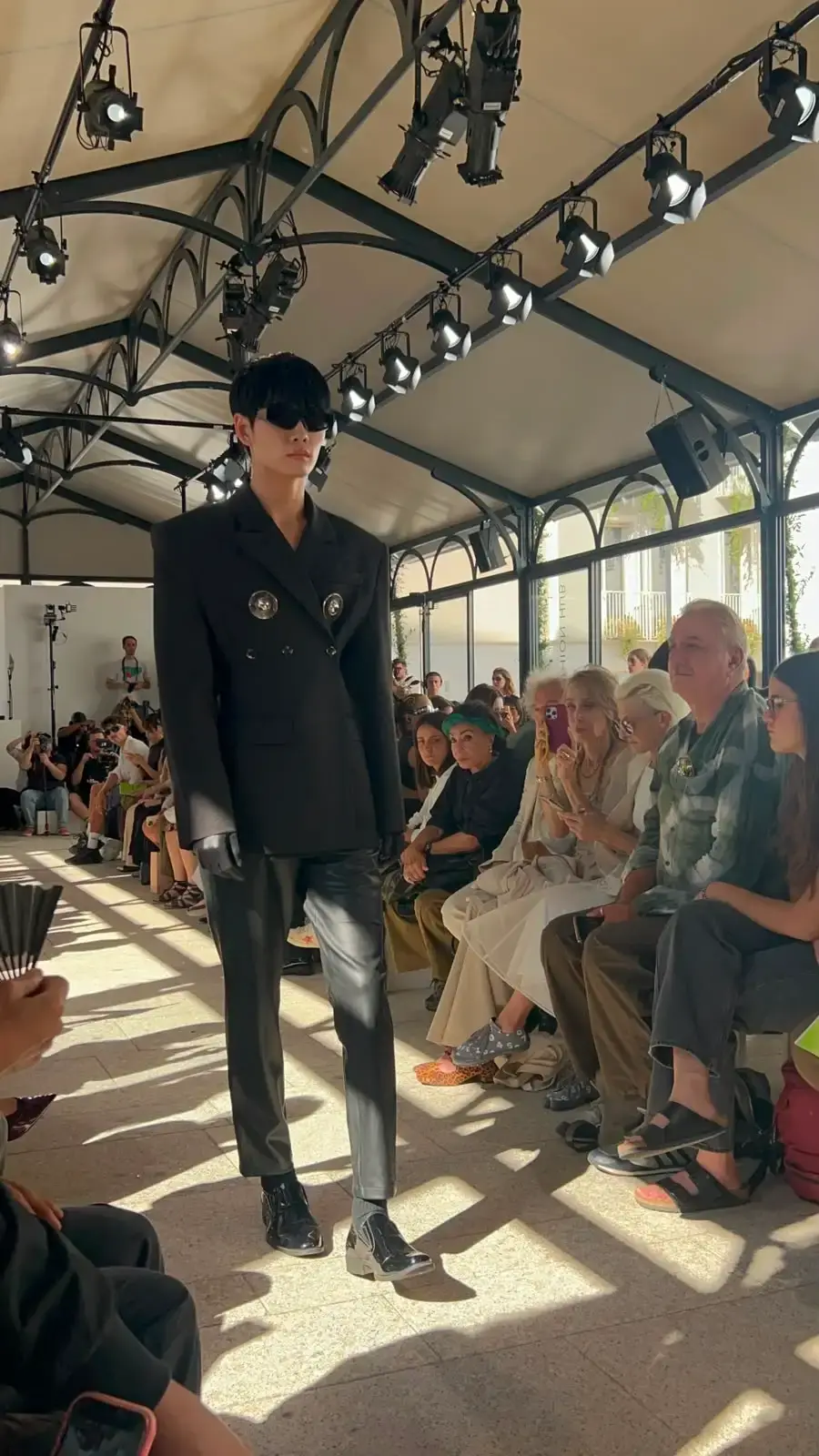 YEZAEL "VERITÀ" COLLECTION BY ANGELO CRUCIANI image of Marche-born designer Angelo Cruciani's "Verità" collection for Yezael presented at Fashion Week 2026. The text describes tailored suits with wide-leg trousers, 3D floral appliqués, an ochre-yellow coat, a pastel-blue Rococo-inspired suit, and contrasting textures combining leather and pearls. Key quotes and philosophical reflections explore fashion, consumerism, nature, and personal identity. (image 9 of 12)