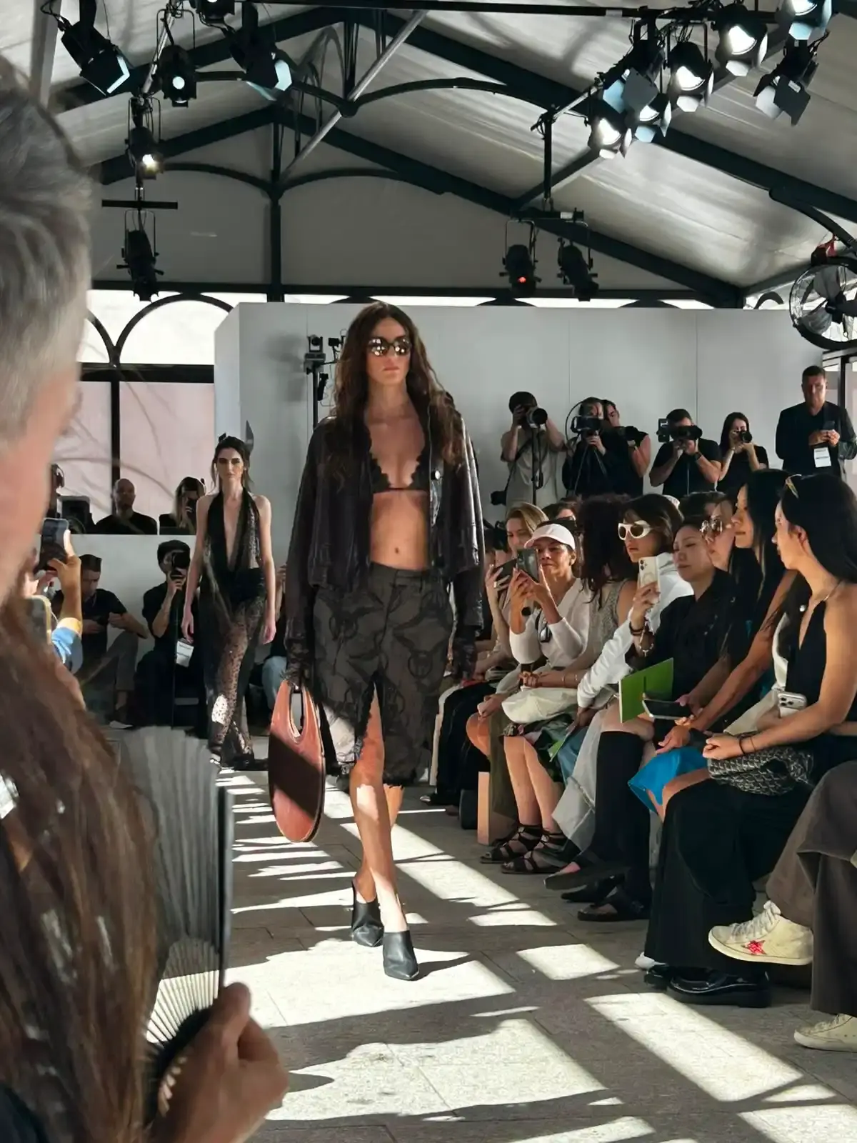 YEZAEL "VERITÀ" COLLECTION BY ANGELO CRUCIANI image of Marche-born designer Angelo Cruciani's "Verità" collection for Yezael presented at Fashion Week 2026. The text describes tailored suits with wide-leg trousers, 3D floral appliqués, an ochre-yellow coat, a pastel-blue Rococo-inspired suit, and contrasting textures combining leather and pearls. Key quotes and philosophical reflections explore fashion, consumerism, nature, and personal identity. (image 5 of 12)