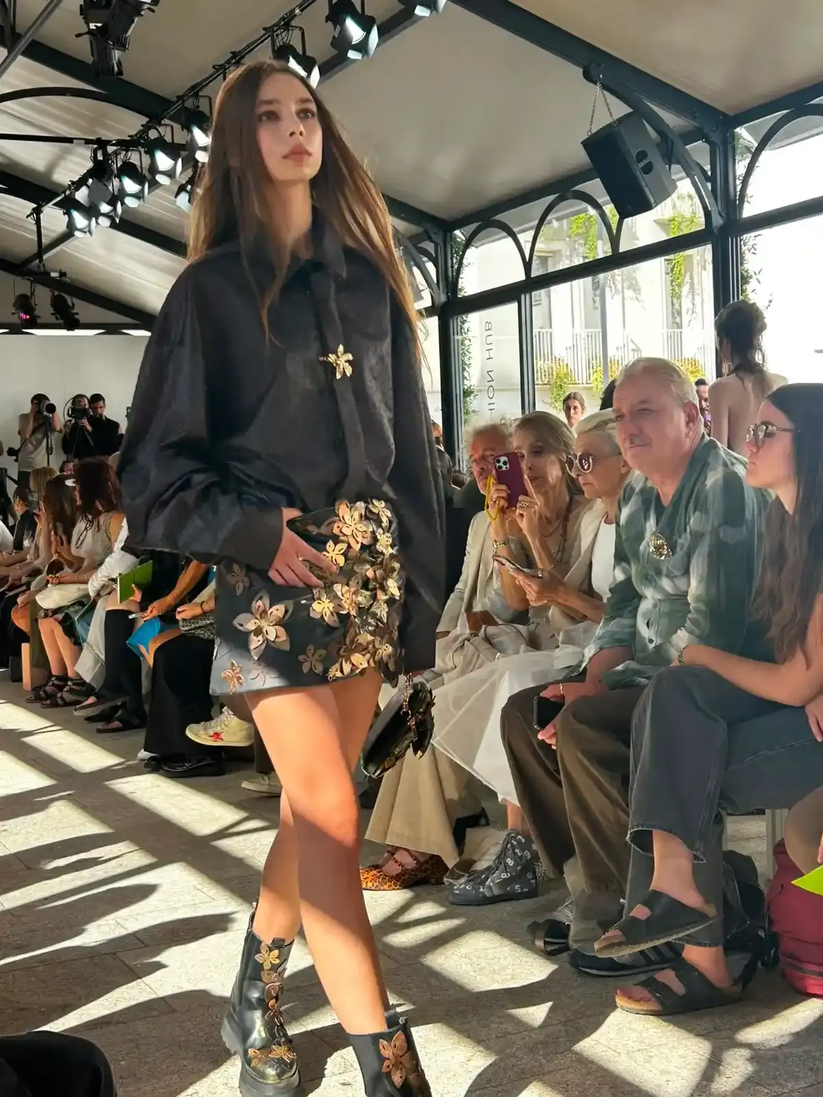 YEZAEL "VERITÀ" COLLECTION BY ANGELO CRUCIANI image of Marche-born designer Angelo Cruciani's "Verità" collection for Yezael presented at Fashion Week 2026. The text describes tailored suits with wide-leg trousers, 3D floral appliqués, an ochre-yellow coat, a pastel-blue Rococo-inspired suit, and contrasting textures combining leather and pearls. Key quotes and philosophical reflections explore fashion, consumerism, nature, and personal identity. (image 4 of 12)